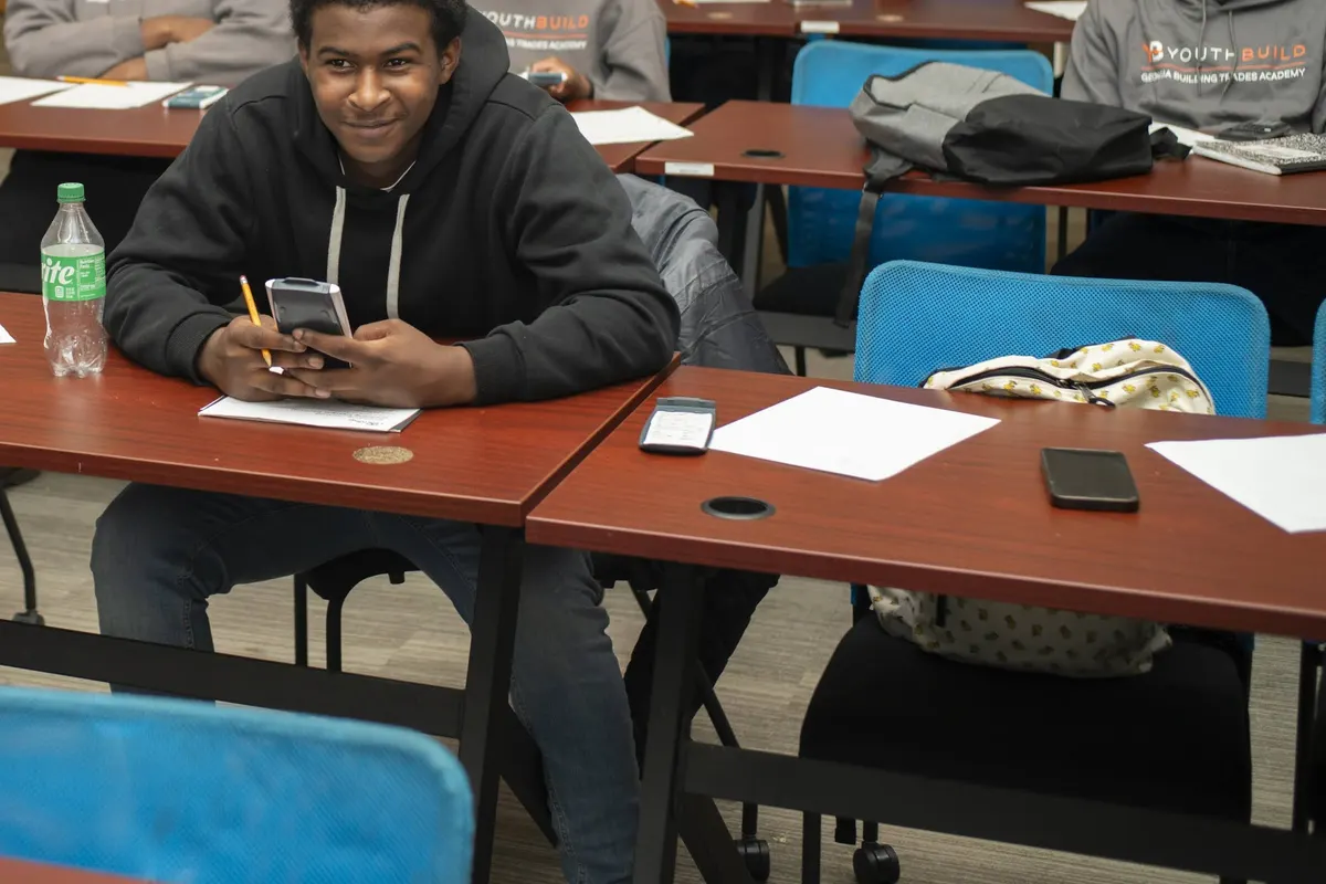 A participant at a classroom table, smiling