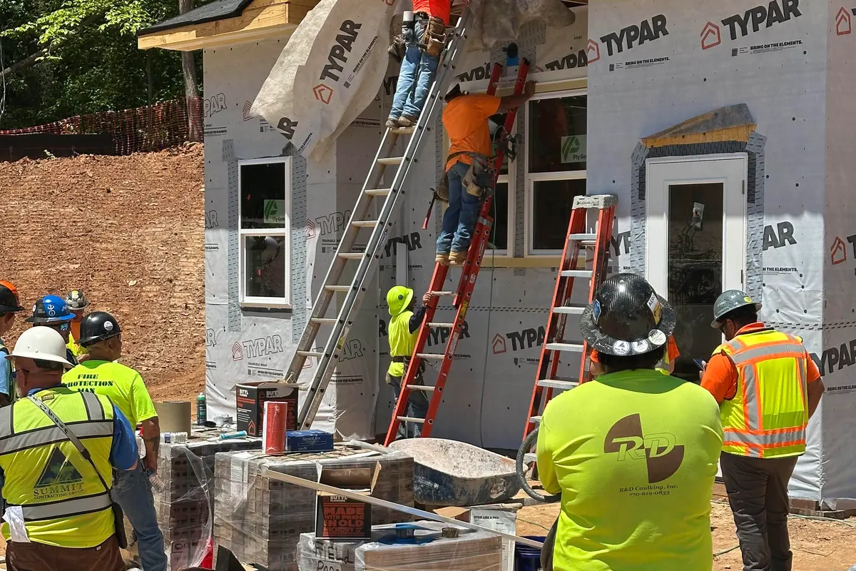 A crew on ladders wrapping a house under construction